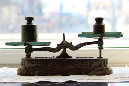 Old scales with cups stand on the windowsill near the window.の写真素材