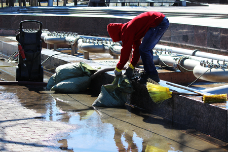 A worker removes debris from the basin pool before washing under pressure from a portable installation in the spring, St. Petersburg.の写真素材