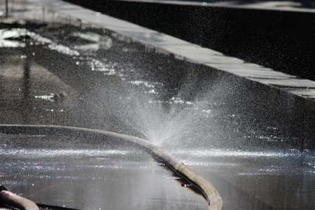 Thin streams of water from the hose in front of the sunlight in the spring while washing the...