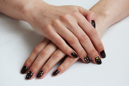 beauty delicate coffee manicure with gold sparkles with gel varnish on a white wall background.の写真素材