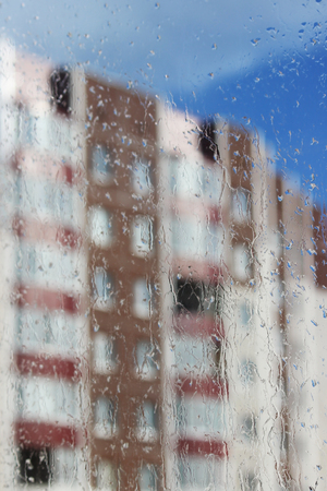 Raindrops on glass and blurred blue sky and house.の写真素材