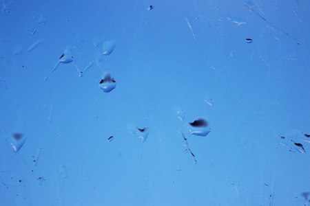 Raindrops on glass and blurred blue skyの写真素材
