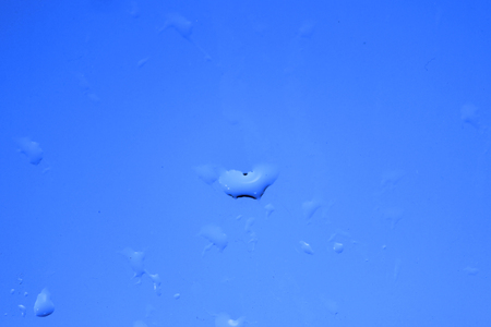 Raindrops on glass and blurred blue skyの写真素材