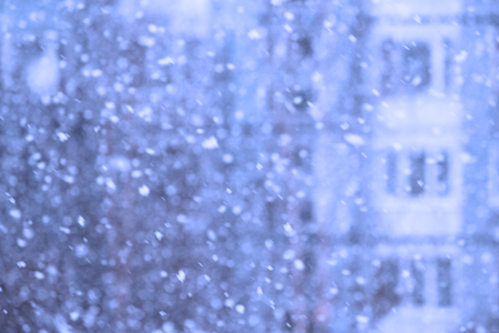 Falling snow flakes during a snowfall in the background of the house.の写真素材