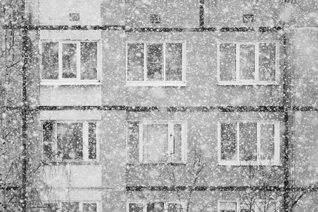 Black and white Falling snow flakes during the snowfall from the sky in the background of the houseの写真素材