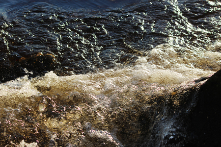 The river brown water of the Northern Dvina River beats against the stone shoreの写真素材