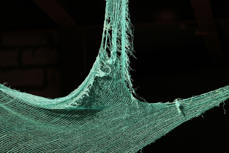 Torn green building mesh on an unguarded unfinished abandoned buildingの写真素材