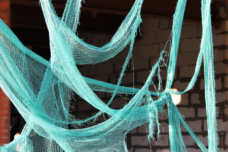 Torn green building mesh on an unguarded unfinished abandoned buildingの写真素材
