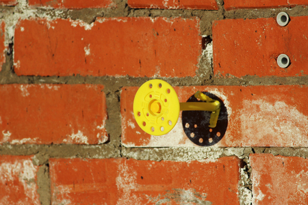 Yellow Mounting pair dowel-nail or disk-shaped dowel rivets with the help of which the mineral wool board is fixed to the wall of the house. Abandoned unfinished building. The view after the plate is dismantled.の写真素材