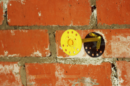 Yellow Mounting pair dowel-nail or disk-shaped dowel rivets with the help of which the mineral wool board is fixed to the wall of the house. Abandoned unfinished building. The view after the plate is dismantled.の写真素材