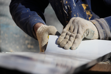 The worker makes the sladding of windows in the restored building in the city, cuts the metal sheet for the slope with scissorsの写真素材