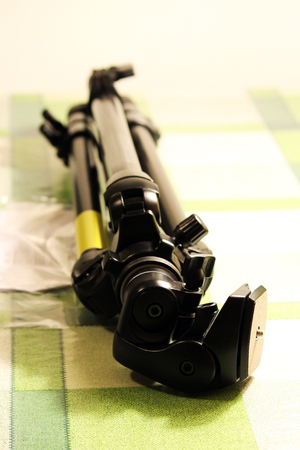 Folded professional tripod for the camera lies on the tableの写真素材