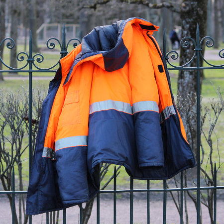 Working blue-orange warm jacket hanging on the fence