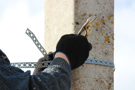 Worker affixes a metal chrome clamp to a post for hanging a road signの写真素材