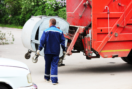 worker loads rubbish bin at a recycling machine.の写真素材
