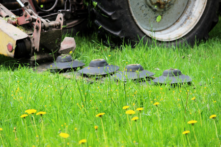The tractor with a special nozzle automatically mows the grass on an urban lawn.の写真素材