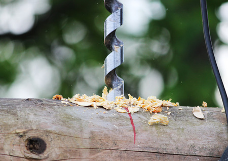 Metal spiral drill for making holes in logs when assembling a wooden frame and building a house.の写真素材