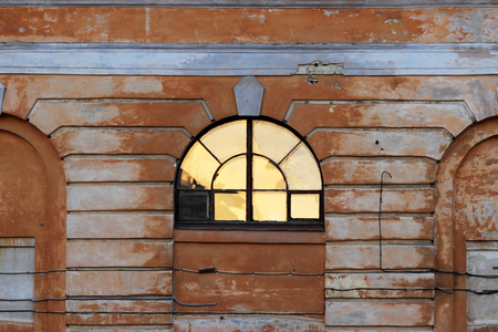 The light from the sun is reflected in the semicircular window of the historic house during sunsetの写真素材
