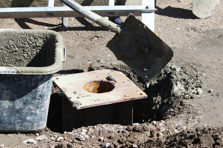 The worker put cement to fix the foundation of the support under the traffic lights near the road with the help of shovel.の写真素材