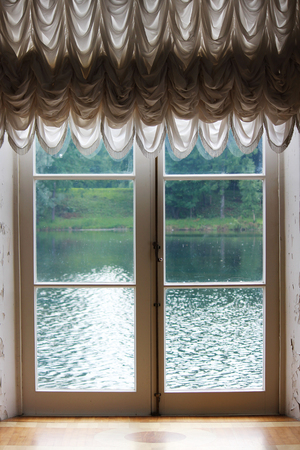 Light from the window with white French curtains and a view of the lake.の写真素材