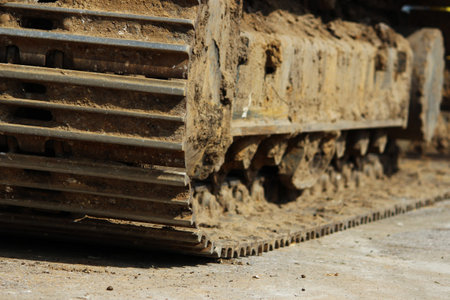 Caterpillars of a large construction dredge who works on a road repair site