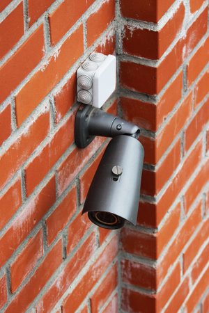 A video camera on a red brick wall protects the territory from the invasion of strangers