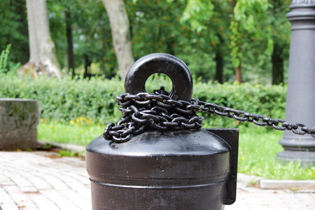 A black metal chain with large links chained to a heavy concrete pedestal. decorative fence in the parkの写真素材