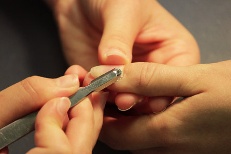 A student at the training courses of a manicure prepares the hand of a lady client with tool for...