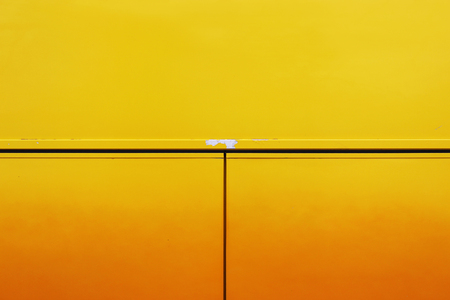 The metal wall of the house, trimmed with colorful panels, painted in bright yellow colors. In one place peeling paint.の写真素材