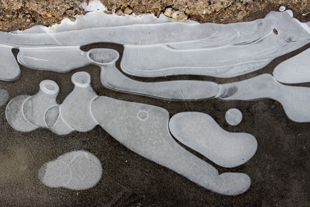 puddle, covered with ice with frozen bubbles in winter. interesting imageの写真素材