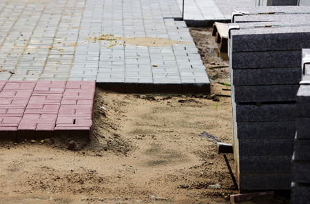 many curbs for construction works on pallets at the site laying paving slabs city square and laid tiles on a layer of sand.の写真素材