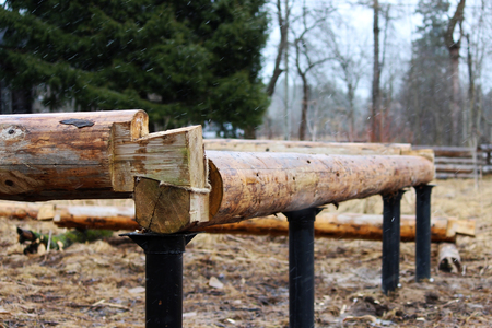 Assembling a wooden frame and building a house. Russia. Texture of old wooden logs and metal columnar base.の写真素材