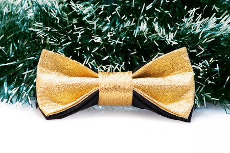 festive gold butterfly bow tie against a background of green Christmas tree tinselの写真素材