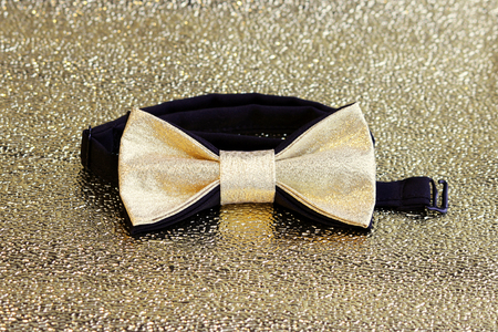 A festive golden with a black bow tie on a gold backgroundの写真素材