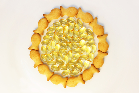 Cod liver oil omega 3 gel capsules and cookies from small fish on white background. round frameの写真素材