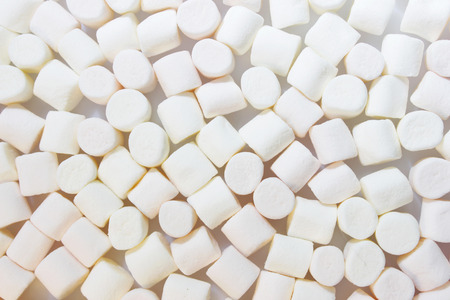 Many small cylindrical pieces of light pink and white marshmallow, confectionery.の写真素材
