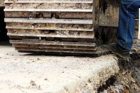 Large construction dredge who works on a road repair site and the drivers foot that sits in the cockpit. Reportage shortting.の写真素材