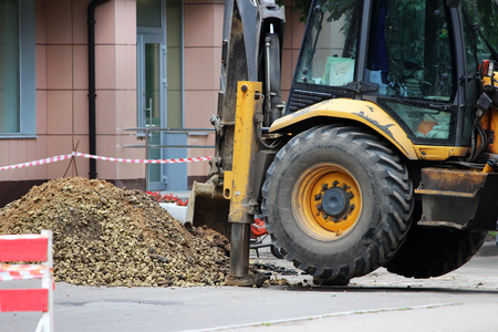 Tractor strong outrigger stabilizing legs extended to stabilize and steady state when digging the soil when eliminating a water supply accidentの写真素材