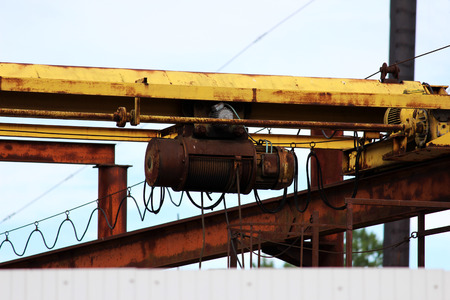 old rusty crane beam in the warehouse under the open sky near the building supermarket for handling operationsの写真素材