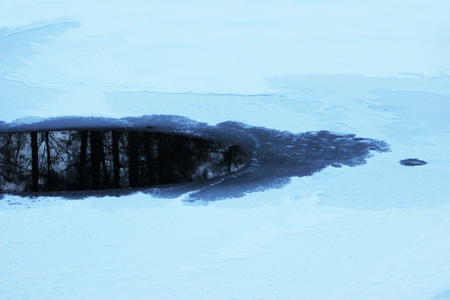 ice-free water on Lake Karpin Pond, Gatchina Park, Russia. The lake is covered with a layer of ice and white snowの写真素材