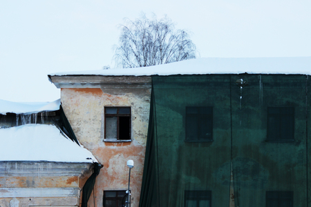 Restoration of the building and a protective green building mesh with frozen water that drained from the roof. Old windowの写真素材