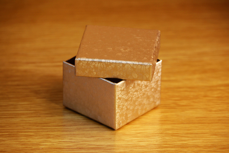 A small golden box on a light yellow wooden background. soft reflective lightの写真素材