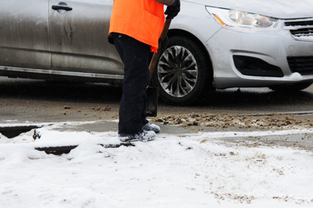 the worker cleans the railway tracks from the snow with a shovel in the place of automobile railway...