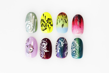 many plastic pink tips for nail extension and training in applying design while training a manicure. trial student work in the form of monograms, flowers and animals, with pasted pastes on a white backgroundの写真素材