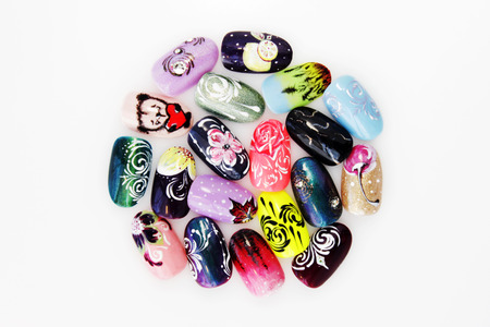 many plastic pink tips for nail extension and training in applying design while training a manicure. trial student work in the form of monograms, flowers and animals, with pasted pastes on a white backgroundの写真素材