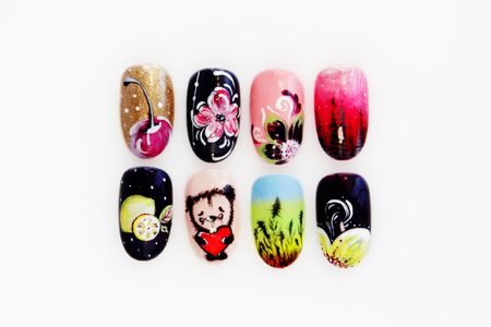 many plastic pink tips for nail extension and training in applying design while training a manicure. trial student work in the form of monograms, flowers and animals, with pasted pastes on a white backgroundの写真素材