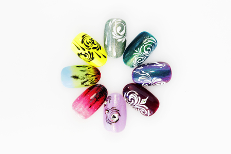 many plastic pink tips for nail extension and training in applying design while training a manicure. trial student work in the form of monograms, flowers and animals, with pasted pastes on a white backgroundの写真素材