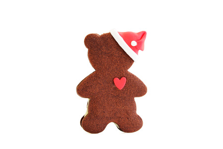 Gingerbread classic cookie in the form of a bear cub with a heart and a New Years cap. Merry Christmas and happy New Year. Isolated.の写真素材