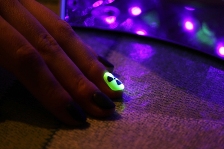 the original manicure in the form of a radioactive danger sign with gel shellac varnish, glows in the dark with ultraviolet lightの写真素材