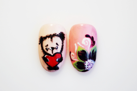 two plastic tips for nail extension and training in applying design while training a manicure on a white background. trial student work in the form of flower and bear cubの写真素材
